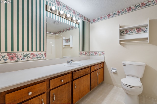 bathroom featuring visible vents, baseboards, toilet, vanity, and a textured ceiling