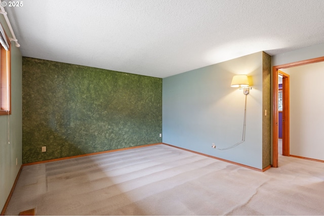 empty room with baseboards, a textured ceiling, and wallpapered walls