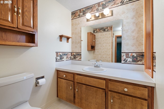 bathroom featuring vanity, toilet, and wallpapered walls