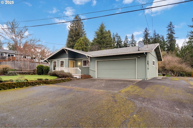 single story home with aphalt driveway, a porch, a garage, and fence