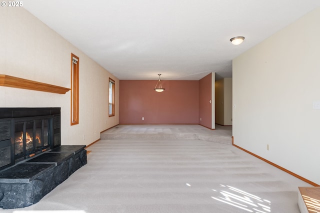 unfurnished living room featuring a glass covered fireplace and baseboards