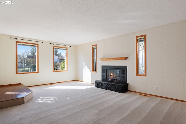 unfurnished living room featuring visible vents, a textured ceiling, carpet flooring, and a tile fireplace