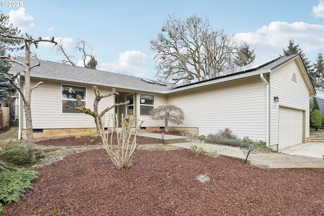 ranch-style home with concrete driveway, a garage, roof mounted solar panels, and crawl space