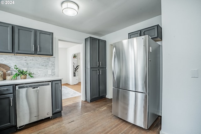 kitchen featuring backsplash, gray cabinets, light wood-type flooring, and stainless steel appliances