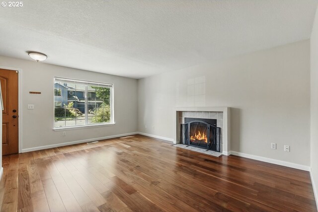 7091 SE Austin Dr, Hillsboro, OR 97123 - unfurnished living room featuring wood finished floors, a tiled fireplace, and a textured ceiling