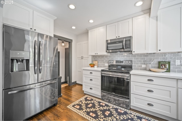 6406 N Michigan Ave, Portland, OR 97217 - kitchen with appliances with stainless steel finishes, white cabinetry, light countertops, backsplash, and dark wood-style flooring