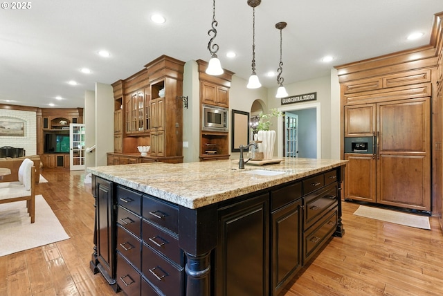 2812 Beacon Hill Dr, West Linn, OR 97068 - kitchen with built in appliances, light wood finished floors, arched walkways, a kitchen island with sink, and light stone countertops