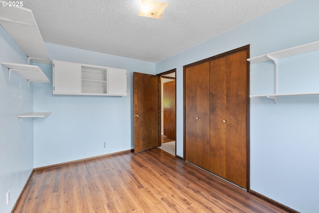 44505 SW Knight Rd, Gaston, OR 97119 - unfurnished bedroom featuring a closet, wood finished floors, a textured ceiling, and baseboards