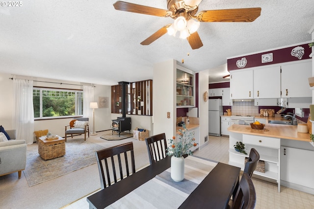 44505 SW Knight Rd, Gaston, OR 97119 - dining area featuring a wood stove, a textured ceiling, ceiling fan, and light carpet