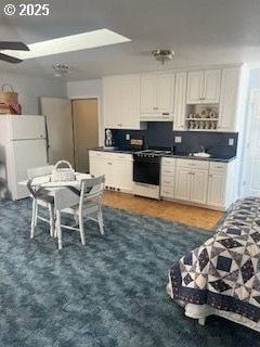 34085 Berg Rd, Warren, OR 97053 - kitchen featuring gas stove, freestanding refrigerator, a ceiling fan, under cabinet range hood, and dark countertops