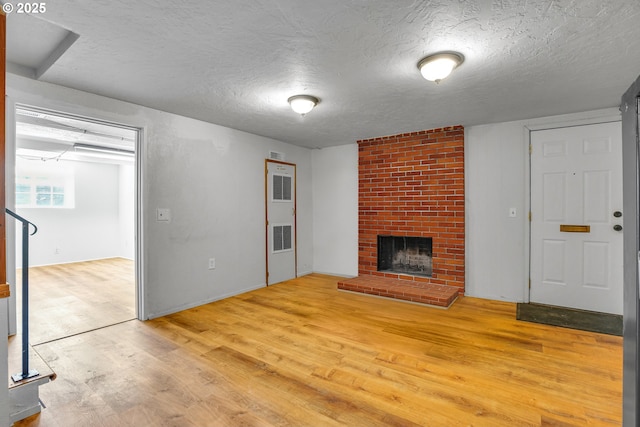 4803 SE Fieldcrest Dr, Milwaukie, OR 97222 - unfurnished living room featuring light wood-style flooring, a textured ceiling, and a brick fireplace
