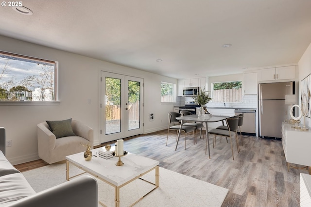 2747 NE Bryant St, Portland, OR 97211 - living room featuring light wood-style flooring, baseboards, and french doors