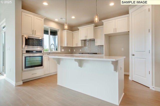 4205 NE 186th St Lot 265, Vancouver, WA 98686 - kitchen with stainless steel appliances, backsplash, light countertops, a breakfast bar, and a kitchen island