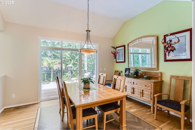 dining space featuring baseboards, visible vents, light wood-style flooring, and vaulted ceiling