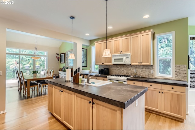 kitchen featuring a sink, light brown cabinetry, and white appliances
