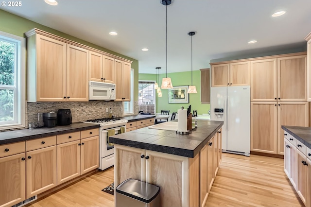 kitchen featuring dark countertops, tasteful backsplash, light wood-type flooring, light brown cabinets, and white appliances
