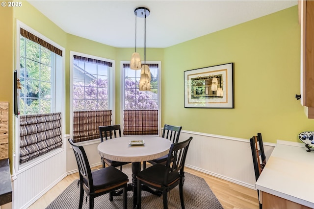 dining space featuring light wood-type flooring and a wainscoted wall