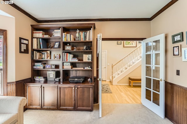 office space featuring crown molding, a wainscoted wall, and light carpet