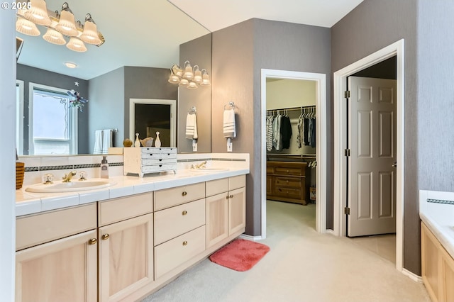 bathroom with double vanity, a chandelier, a sink, and a spacious closet