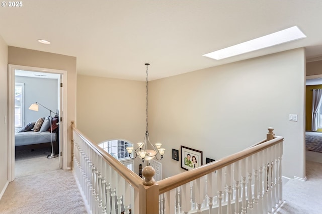hall featuring recessed lighting, an upstairs landing, a chandelier, carpet flooring, and a skylight