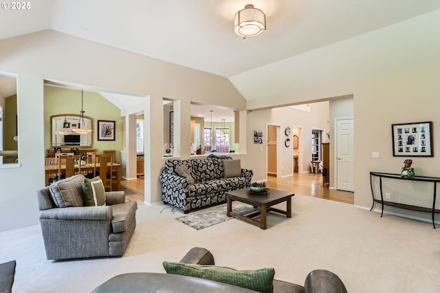 carpeted living area featuring baseboards and vaulted ceiling