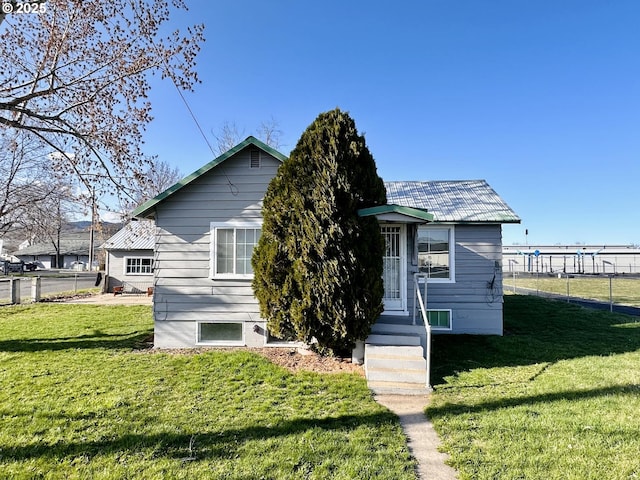 view of front of house with a front lawn, fence, and metal roof