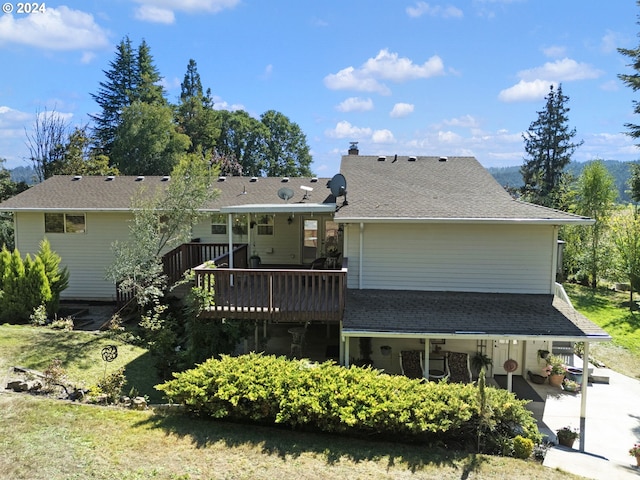 rear view of property featuring a shingled roof and a wooden deck