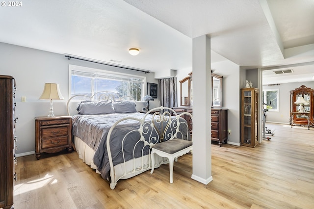 bedroom with light wood-style floors, visible vents, multiple windows, and baseboards