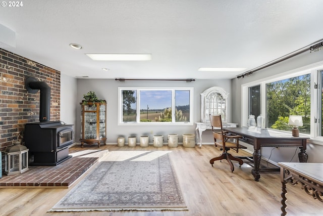 sitting room with a wood stove, plenty of natural light, baseboards, and wood finished floors