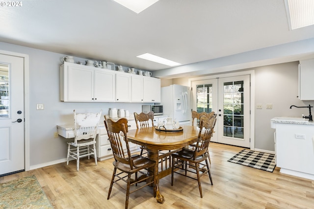 dining area featuring french doors, light wood-type flooring, and baseboards