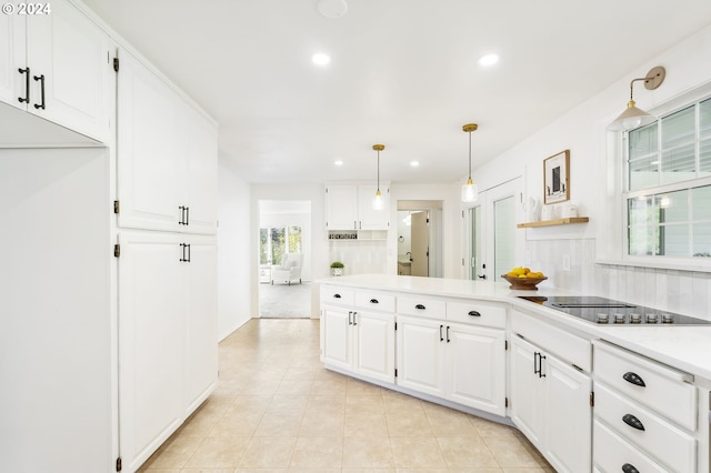 kitchen featuring white cabinets, black electric stovetop, light countertops, and backsplash