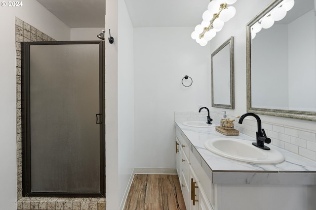 bathroom with double vanity, a sink, a shower stall, and wood finished floors