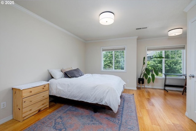 bedroom with multiple windows, ornamental molding, light wood-type flooring, and baseboards