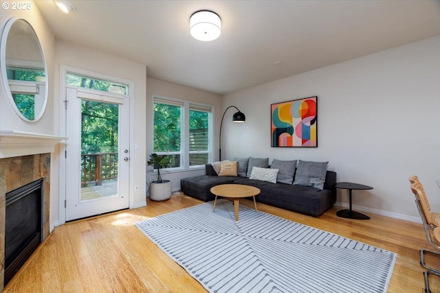 living room featuring wood finished floors, a tile fireplace, and baseboards
