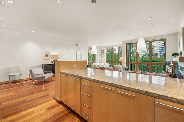 1030 NW Johnson St Unit 323, Portland, OR 97209 - kitchen featuring light wood finished floors, light stone counters, recessed lighting, pendant lighting, and open floor plan