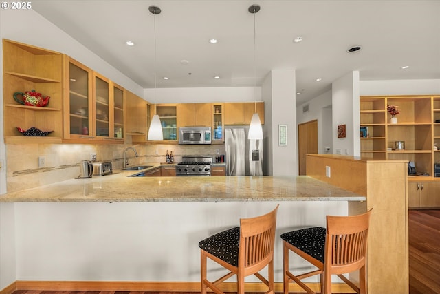 1030 NW Johnson St Unit 323, Portland, OR 97209 - kitchen with appliances with stainless steel finishes, a sink, a peninsula, backsplash, and light stone counters