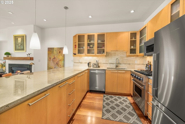 1030 NW Johnson St Unit 323, Portland, OR 97209 - kitchen with appliances with stainless steel finishes, a sink, wood finished floors, light stone counters, and recessed lighting