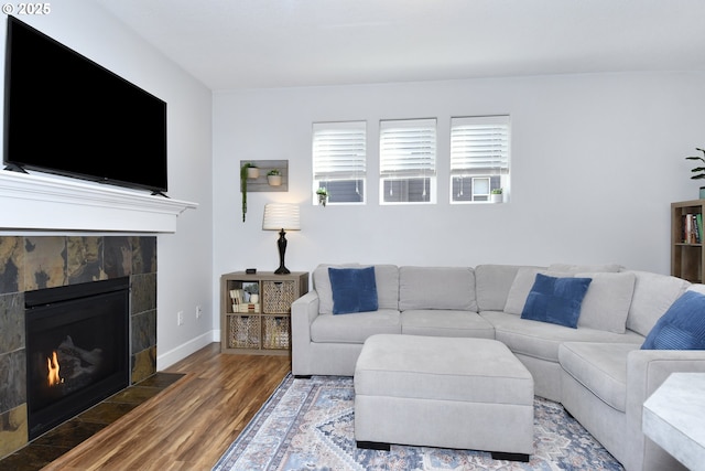 living room with a tiled fireplace and dark wood-type flooring