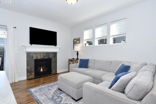 living room with a healthy amount of sunlight, dark hardwood / wood-style floors, and a tiled fireplace