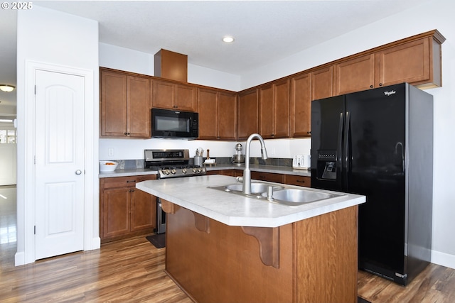 kitchen with sink, a center island with sink, dark hardwood / wood-style floors, and black appliances