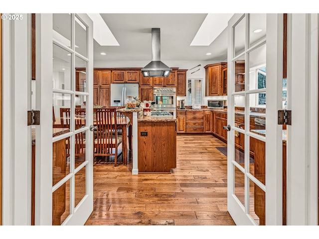 kitchen featuring french doors, light wood finished floors, brown cabinets, and stainless steel appliances
