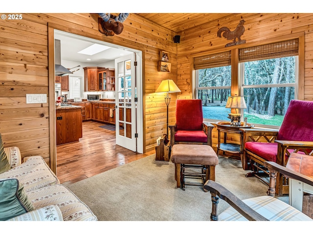 living area featuring a skylight, wood walls, and wood finished floors