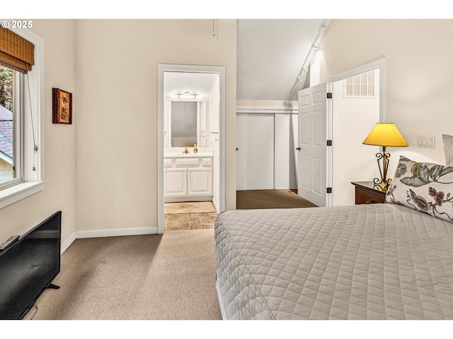bedroom featuring a closet, carpet flooring, baseboards, and ensuite bath