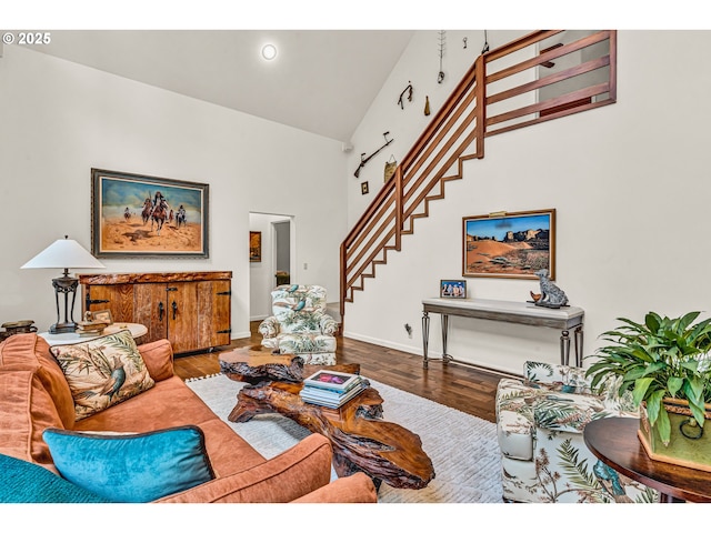living area featuring stairway, high vaulted ceiling, baseboards, and wood finished floors