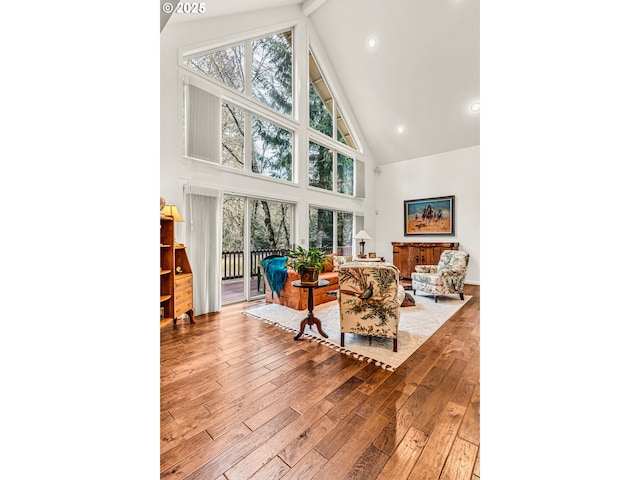 living room featuring a healthy amount of sunlight, high vaulted ceiling, recessed lighting, and hardwood / wood-style flooring