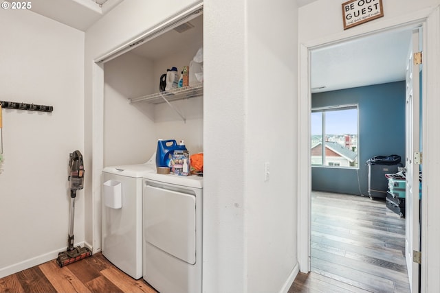 laundry room with baseboards, laundry area, washing machine and dryer, and wood finished floors