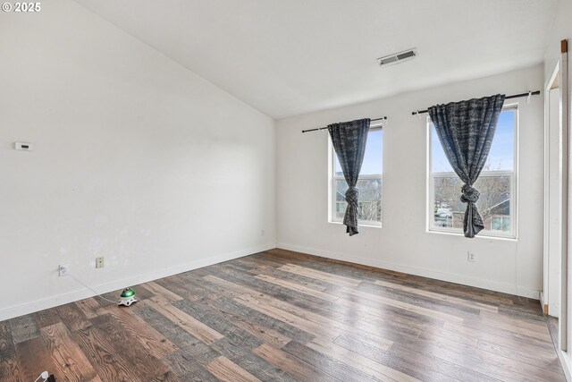 empty room featuring hardwood / wood-style flooring, baseboards, visible vents, and lofted ceiling