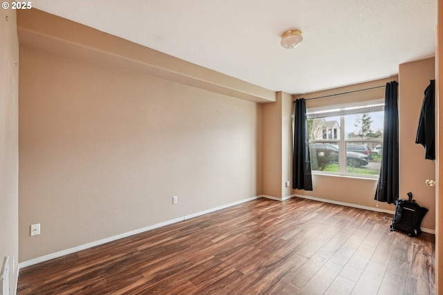 spare room featuring wood finished floors and baseboards