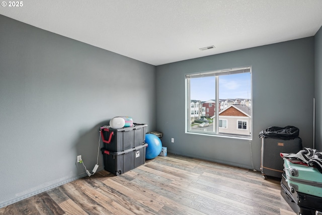 interior space with visible vents, baseboards, a textured ceiling, and wood finished floors