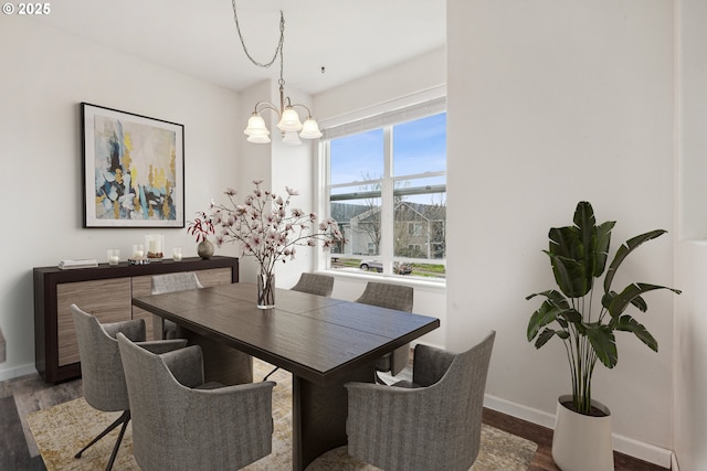 dining space featuring baseboards, a notable chandelier, and wood finished floors